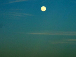 De volle maan toont zich boven het strand.