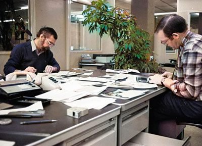 Collegas Jan Fokker en Cees van Cuylenburg aan het werk. Nu pas zie ik dat we ook planten hadden. Kan me niet herinneren wie die dan water heeft gegeven.