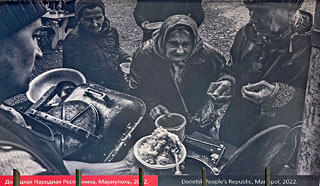 Een vrouw bij een veldkeuken. Een beeld dat voor de val van Marioepol ook al vertrouwd was, toen de Russen de stad al goeddeels in puin hadden geschoten.