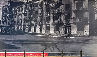 Verwoesting in Marioepol in 2022. Een kapot gebouw in een door de Russen geru�neerde stad waar Oekra�ense troepen nog nauwelijks schade kunnen aanrichten. Onderin de foto de spijlen van het ambassadehek.