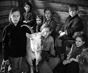 De zeven kinderen en een geit verstoppen zich voor de dorpsraad bij een oude schoenlapper.